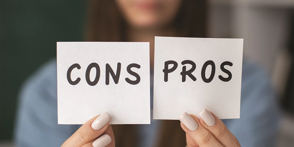 Person holding cards labelled Cons and Pros - pros and cons of hiring a professional resume writer