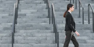 Professional woman walking up stairs confidently — career change momentum guide