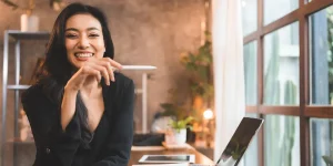 Professional smiling at camera with LinkedIn profile on laptop screen — LinkedIn profile stand out