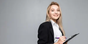 Smiling professional woman in business attire holding a clipboard — 10 practical resume writing tips for 2025