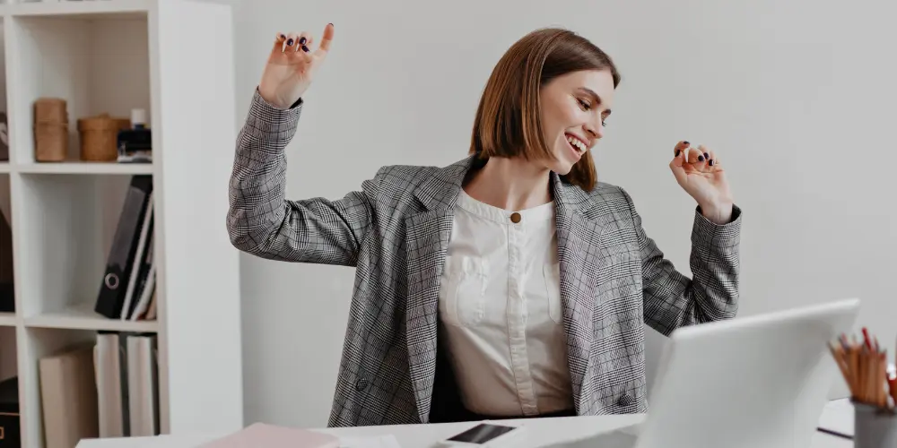 Excited professional woman celebrating success at a laptop — identify your unique value proposition before applying for a job