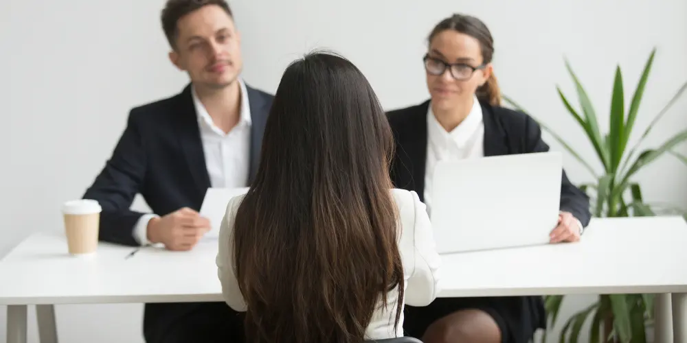 Job candidate in an interview meeting with two professionals — write a compelling cover letter for your job application