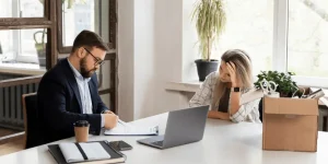 Stressed employee at a desk with a cardboard box after a layoff — how to handle a layoff and face the job search