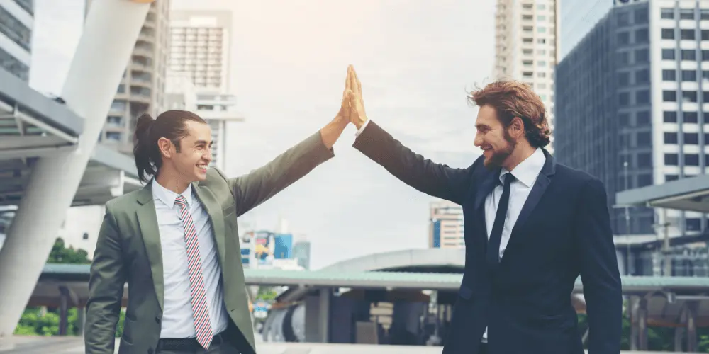 Two professionals high-fiving outdoors in front of city buildings — how to write a resume for the healthcare industry