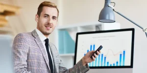 Finance professional pointing at bar charts on a monitor — how to write a resume for the finance industry