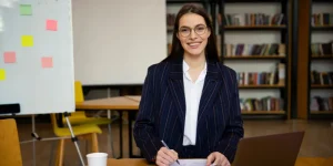 Female teacher in blazer standing in a library classroom — how to create a resume for the education industry
