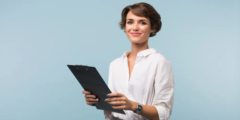 Professional woman in white blouse holding clipboard against light blue background — 30 resume writing tips for 2025