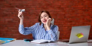 Excited woman at desk holding toy airplane and celebrating — how to score your dream job in 2025