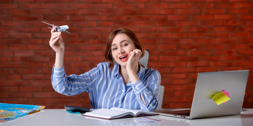 Excited woman at desk holding toy airplane and celebrating — how to score your dream job in 2025