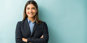 Confident professional woman in blazer with arms crossed against teal background — how to build a personal brand