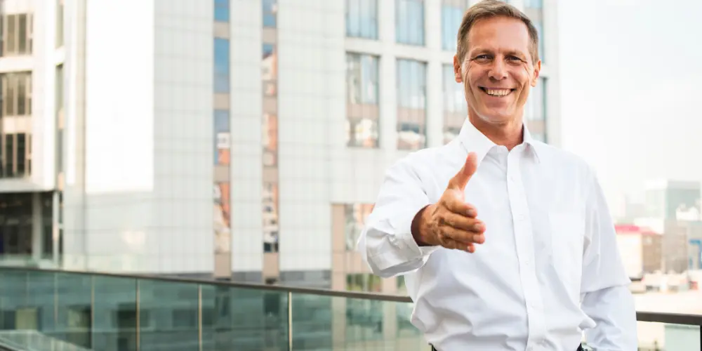 Confident CEO in white shirt giving thumbs up in front of a modern office building — building a strong CEO legacy
