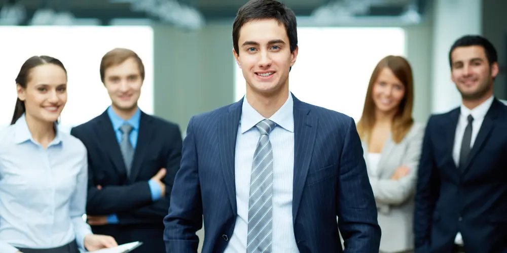 Young male manager leading a team of business professionals in suits — common mistakes new managers make and how to avoid them