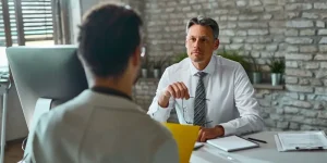 Job candidate sitting across from interviewer at a desk during a professional job interview — how to crack an interview