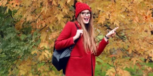 Happy woman in red coat among autumn leaves - this fall is the best time to update your resume for the hiring season