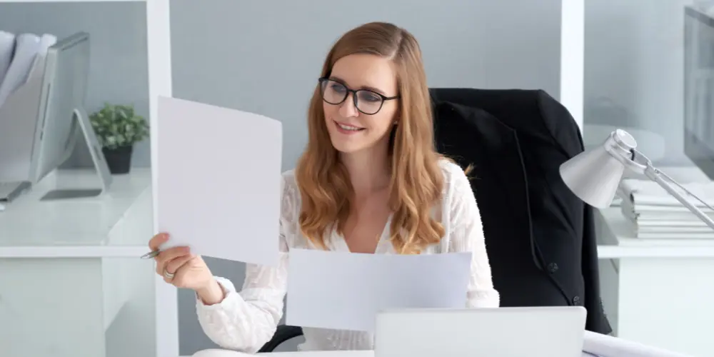 Professional woman reviewing a resume document at her desk - tips to make your resume ATS friendly