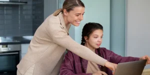 Mother helping daughter write her first resume on a laptop - first resume tips from an HR professional