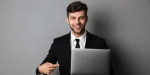 Confident sales manager in a suit smiling with a laptop — what to show on a sales manager resume