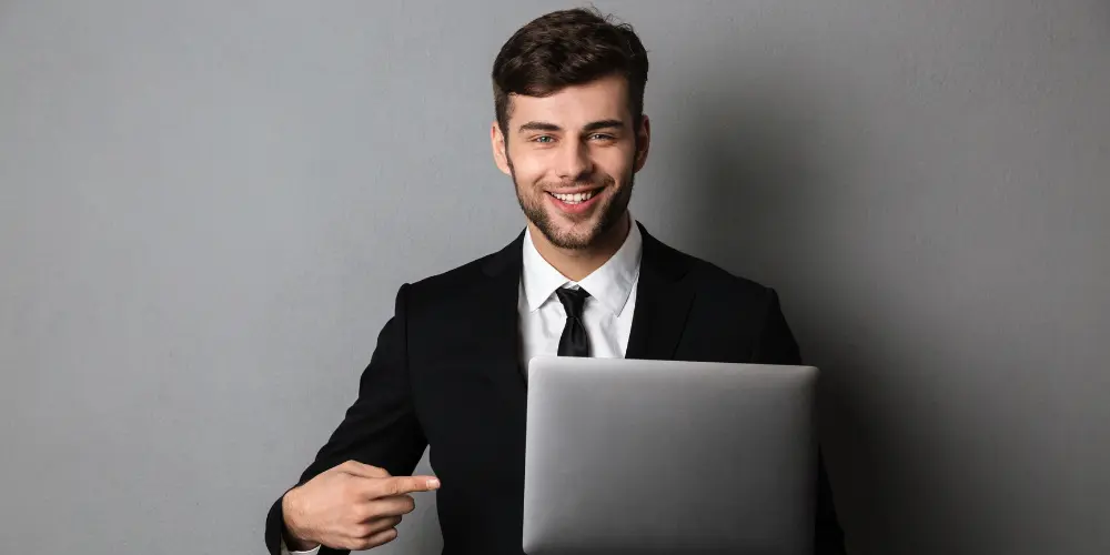 Confident sales manager in a suit smiling with a laptop — what to show on a sales manager resume