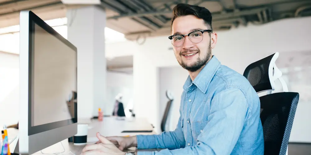 Smiling software engineer at his computer - software engineer resume tips to land big tech job offers at Microsoft Amazon and eBay