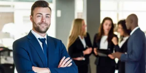 Confident sales manager standing with arms crossed in a business office — best resume keywords for sales managers